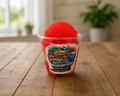 Red Cherry Philadelphia-style water ice in Shai’s Philly 2TX branded cup on rustic wooden farmhouse table, colorful Italian ice dessert with soft natural lighting and vibrant frozen treat texture.